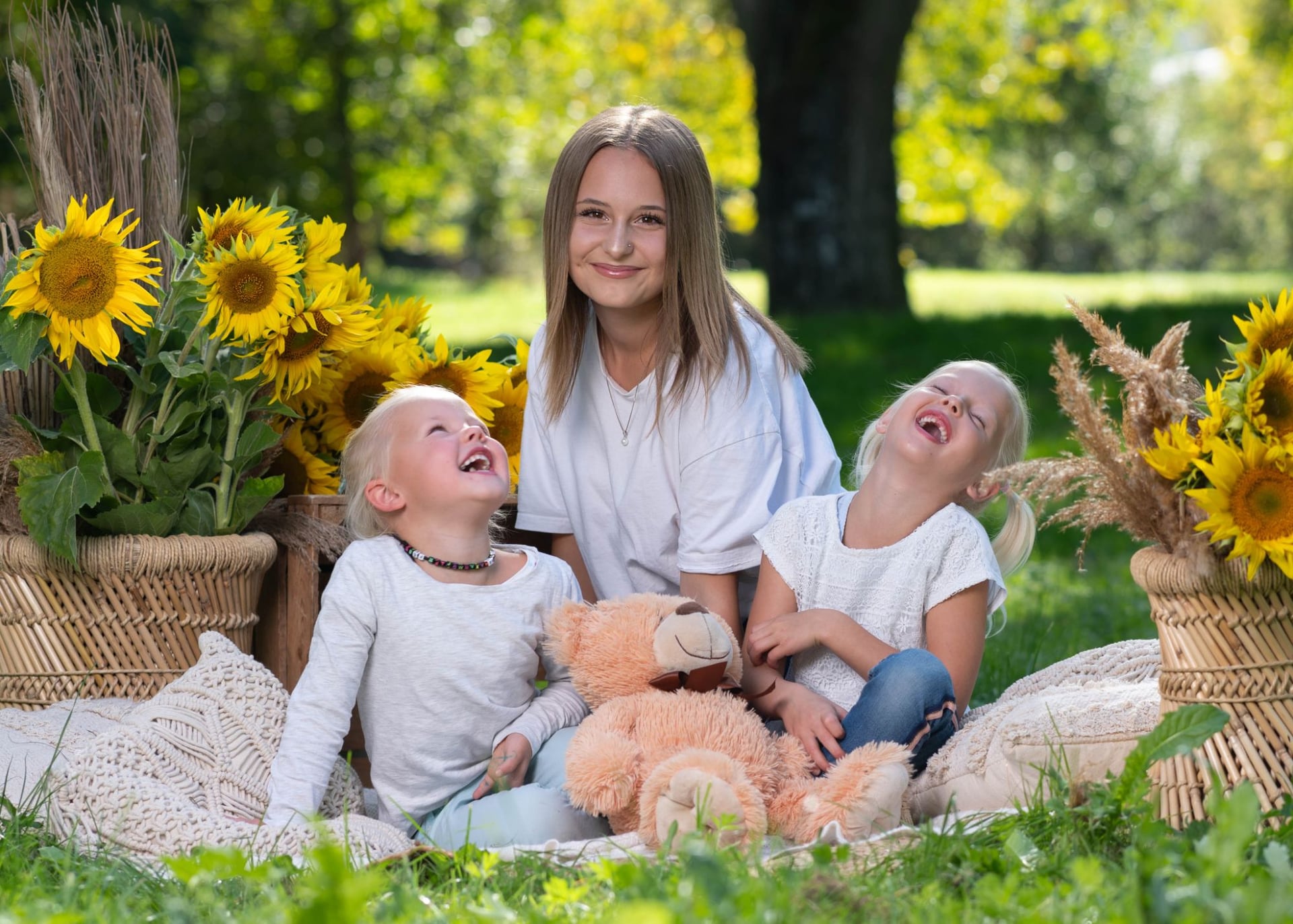 Drei Schwestern lachen ausgelassen zwischen Sonnenblumen